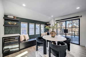 Dining area featuring vaulted ceiling, beverage cooler, and light wood-type flooring