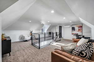 Interior space featuring vaulted ceiling and a wall unit AC