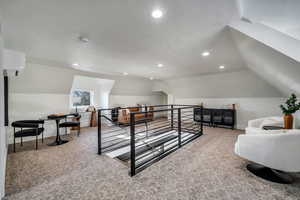 Interior space featuring vaulted ceiling, carpet flooring, and a wall mounted air conditioner