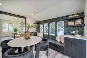 Dining space with light hardwood / wood-style flooring and vaulted ceiling