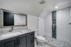 Bathroom with vanity, toilet, and tiled shower