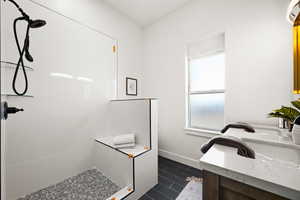 Bathroom with vanity, tile patterned flooring, and a tile shower