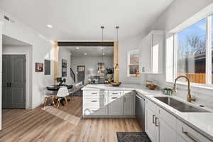 Kitchen featuring white cabinetry, stainless steel dishwasher, sink, and hanging light fixtures