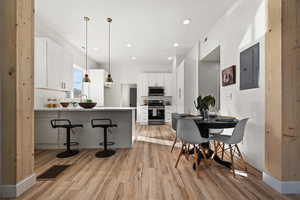 Kitchen featuring a breakfast bar, white cabinets, hanging light fixtures, kitchen peninsula, and stainless steel appliances