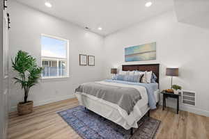 Bedroom featuring a barn door and light wood-type flooring