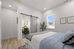 Bedroom with a barn door and light wood-type flooring