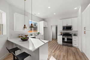 Kitchen with sink, a breakfast bar, appliances with stainless steel finishes, decorative light fixtures, and kitchen peninsula