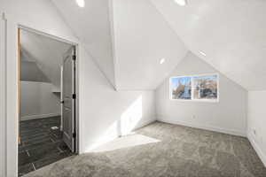 Bonus room with lofted ceiling, dark carpet, and a textured ceiling