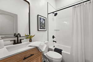 Full bathroom featuring vanity, shower / bath combination with curtain, and toilet