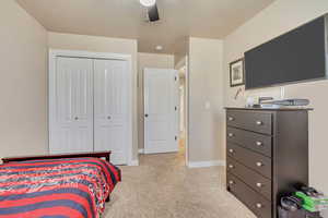 Bedroom featuring ceiling fan, light carpet, and a closet