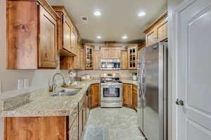 Kitchen featuring sink, stainless steel appliances, and light stone countertops