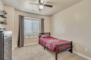 Carpeted bedroom featuring ceiling fan