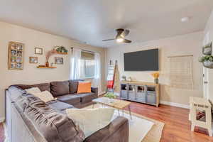 Living room with ceiling fan and light hardwood / wood-style floors