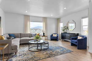 Living room with a textured ceiling and light hardwood / wood-style flooring