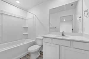 Full bathroom featuring toilet, vanity, shower / washtub combination, and hardwood / wood-style floors