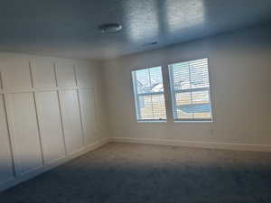 Unfurnished room featuring carpet floors and a textured ceiling