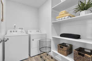 Laundry room with washing machine and clothes dryer and light wood-type flooring