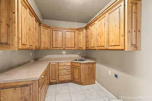 Washroom featuring sink, cabinets, light tile patterned floors, hookup for an electric dryer, and a textured ceiling