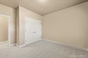 Unfurnished bedroom featuring light colored carpet and a closet