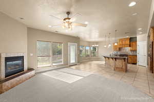 Tiled living room featuring sink, ceiling fan with notable chandelier, a tile fireplace, and a textured ceiling