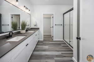 Bathroom with hardwood / wood-style flooring, vanity, and a shower with door