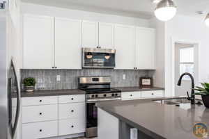 Kitchen with sink, white cabinets, and appliances with stainless steel finishes