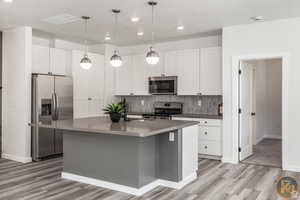 Kitchen featuring appliances with stainless steel finishes, sink, a center island with sink, and white cabinets