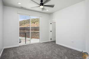 Unfurnished room with ceiling fan and dark colored carpet