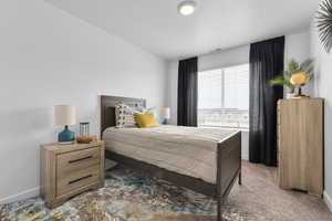 Bedroom with vaulted ceiling, a textured ceiling, and carpet