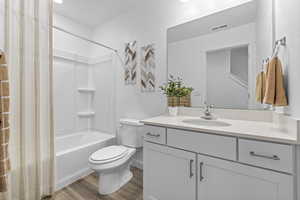 Full bathroom featuring vanity, wood-type flooring, washtub / shower combination, and toilet