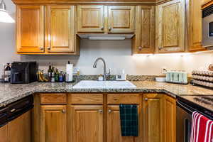 Kitchen with sink, light stone counters, and stainless steel electric range