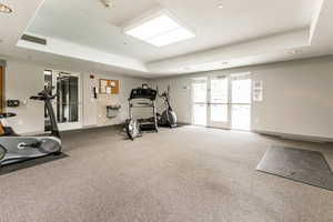 Exercise room with carpet floors and a tray ceiling