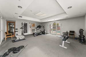 Gym featuring a tray ceiling and french doors