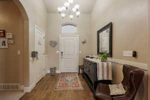 Foyer featuring dark wood-type flooring and a chandelier