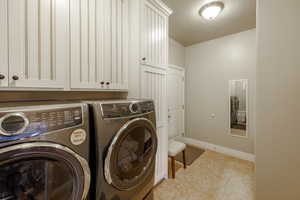 Laundry room featuring separate washer and dryer, cabinets, and a tile floors