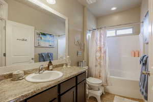 Full bathroom featuring large shower / tub combo, vanity, and tile floors.