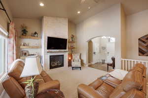 Living room with a fireplace, lofted ceiling, and ceiling fan