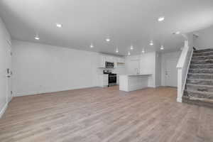 Unfurnished living room featuring sink and light hardwood / wood-style floors