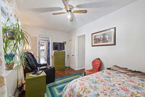 Bedroom with dark wood-type flooring, ceiling fan, and a textured ceiling