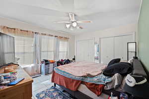 Tiled bedroom featuring ceiling fan and two closets