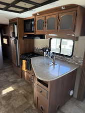 Kitchen featuring stovetop, black microwave, and exhaust hood