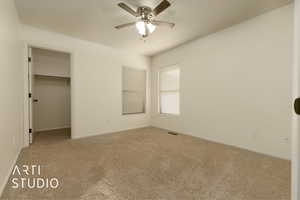 Unfurnished bedroom with ceiling fan, carpet flooring, a closet, and a spacious closet