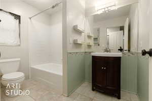 Full bathroom with vanity, tile patterned floors, toilet, and washtub / shower combination