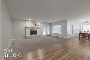 Unfurnished living room with carpet flooring, a textured ceiling, a fireplace, and french doors