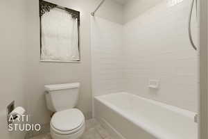 Bathroom featuring tile patterned flooring, tiled shower / bath, and toilet