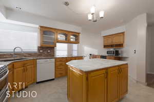 Kitchen featuring a kitchen island, appliances with stainless steel finishes, decorative light fixtures, tasteful backsplash, and a chandelier