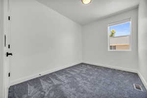 Empty room featuring dark colored carpet