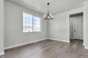 Spare room featuring a notable chandelier, baseboards, and wood finished floors