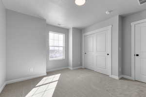 Unfurnished bedroom with baseboards, visible vents, and light carpet
