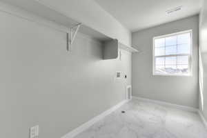 Laundry room with electric dryer hookup, marble finish floor, baseboards, hookup for a washing machine, and laundry area